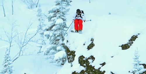Skier Jumps Off Snowy Rock in Winter Wonderland
