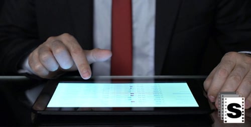 Adult Analyzes Data on Tablet at Desk