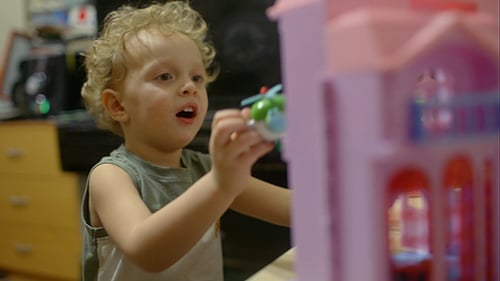 Boy Playing with a Pink Doll House