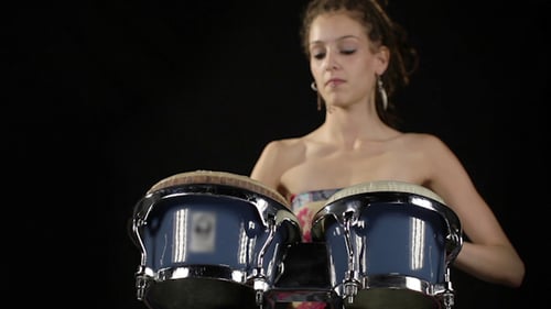 Woman Plays Bongos in Front of Black Backdrop