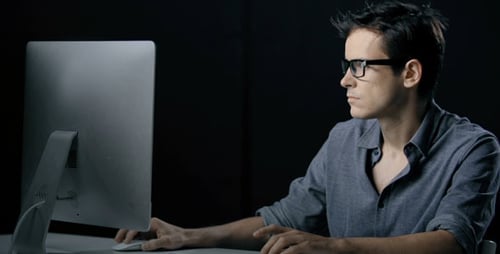 Adult Working on Computer at Desk With Glasses