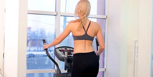 Woman Works Out on Elliptical in Gym