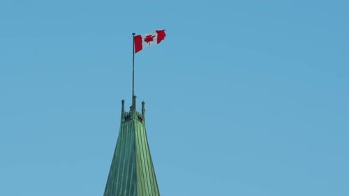 Canadian Flag Waving Atop Building on Sunny Day