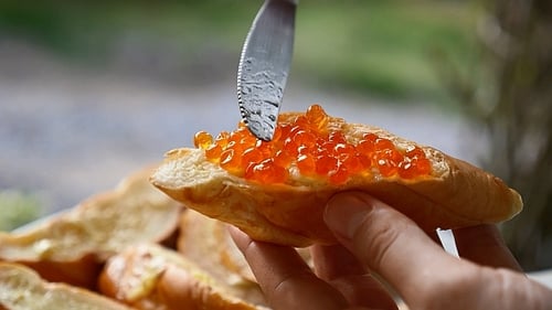 Caviar being added to bread slice with knife