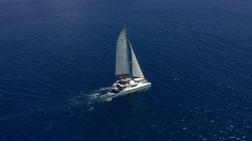 Aerial Footage Rear View of Luxury Sailboat Sailing on a Deep Blue Sea with White Wakes