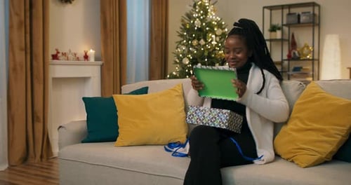 Woman Opens Christmas Gift in Decorated Living Room