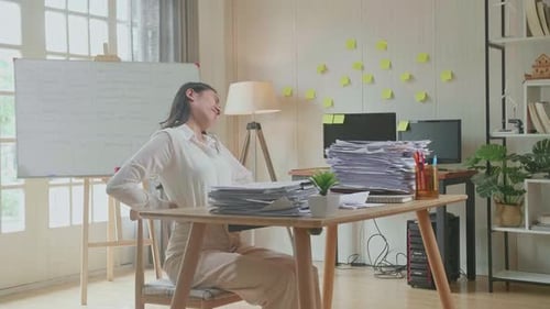 Asian Woman Having Backache While Working Hard With Documents At The Office