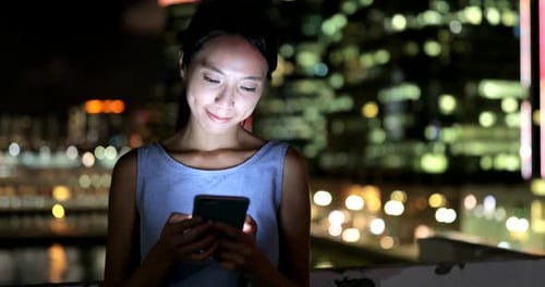 Woman use of mobile phone in city at night
