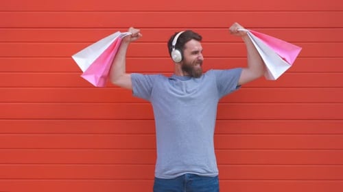 Man with Shopping Bags and Headphones Expresses Joy
