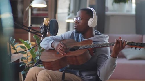 Man on Wheelchair Playing the Guitar and Singing in Home Studio