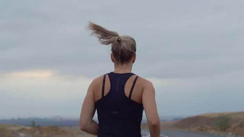 Woman Performs Cardio Training While Jogging Outdoors Background Cloudy Sky Back View