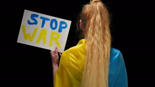 Rückansicht Frau in blau-gelber ukrainischer Flagge zeigt Stop-Kriegs-Banner