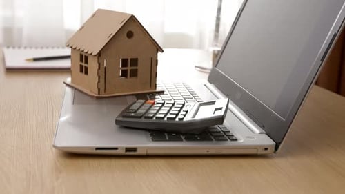 House model and calculator on laptop. The concept of buying a house, mortgage, real estate