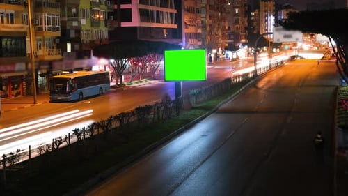 Time Lapse of Blank Billboard with a Green Screen on Night Street with light trails.
