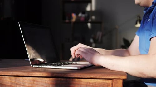 Man Working on Laptop at Wooden Desk