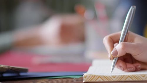 Hand of Young Woman Writing in Notebook