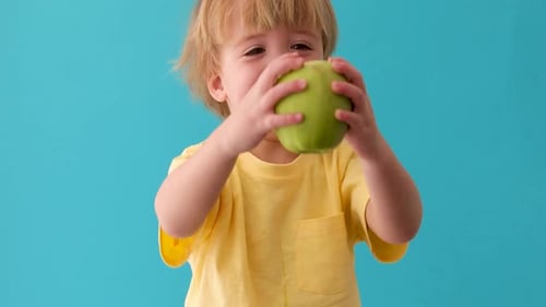 Kleiner Junge hält einen großen grünen Apfel