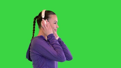 Young Athletic Girl on a Walk with Headphones on a Green Screen Chroma Key