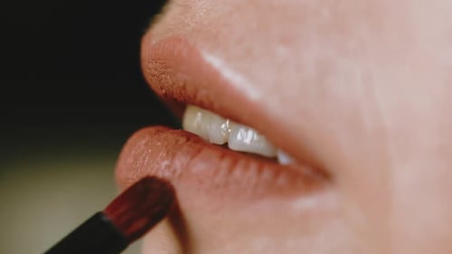 Woman Applies Lipstick with Brush in Close Up