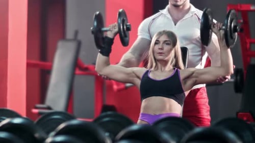 Woman with Her Personal Trainer in the Gym Exercising with Barbells