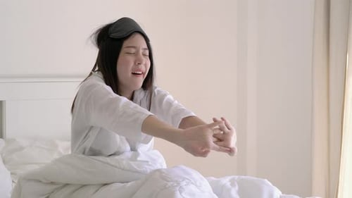 Woman Wakes up and Stretches in Bed