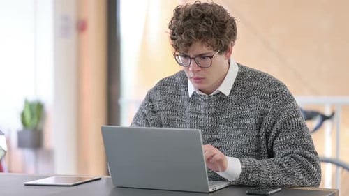Young Adult Using Laptop at Office Desk
