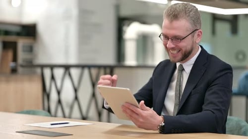 Excited Businessman Celebrating Success on Tablet in Office