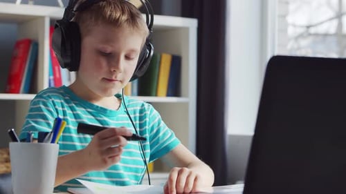 Boy Drawing in Notebook Wearing Headphones Indoors