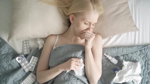 Young Woman is Sick and Lies in Bed Top View