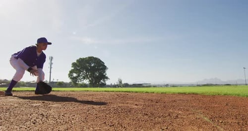 Jardinero de béisbol femenino de raza mixta atrapando y lanzando pelota en un soleado campo de béisbol
