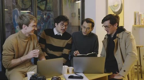 Thoughtful Businessmen Having Working Meeting in Cafe. Business Men Using Laptop