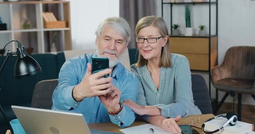 Pareja madura sonriente con teléfono inteligente para tomar selfies