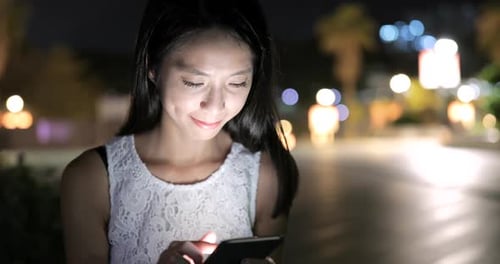 Woman using smart phone in city at night