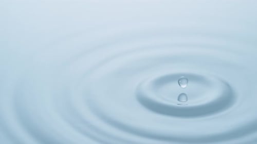 Water Drop Creates Ripples in a Light Blue Pool