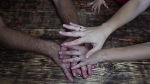 Family Stacking Hands in Unity on Table