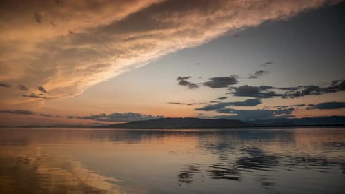 Sunset Over Calm Water Reflecting Orange Sky