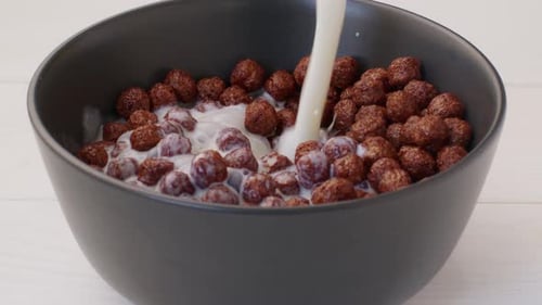 Milk Poured Into Bowl of Chocolate Cereal Balls