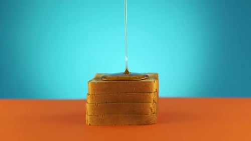 Liquid Honey Pouring on a Piece Bread