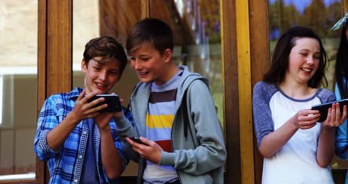 Group of school friends using mobile phone outside school