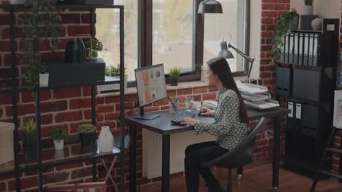 Young Woman Working in Office Raises Arms in Celebration