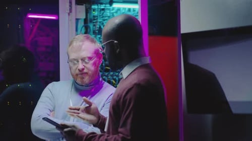 Men Discuss Data on Tablet in Modern Data Center