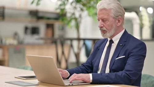 Mature Adult Working at Laptop Smiling Warmly