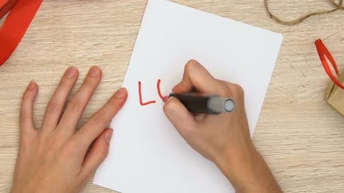 Hand writes love on a piece of paper