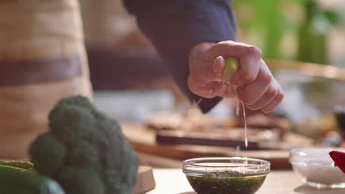 Chef Squeezing Lemon Juice into Bowl with Sauce