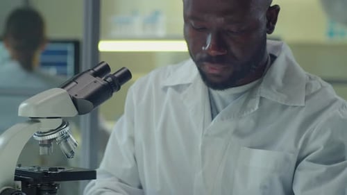 Scientist Concentrating on Microscope Research in Laboratory