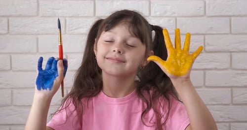 Girl Smiling With Painted Hands and Brush