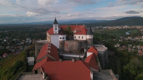 Luftaufnahme der mittelalterlichen Burg auf einem Berg in einer kleinen europäischen Stadt am bewölkten Herbsttag