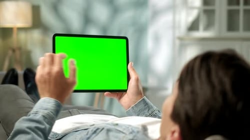 View From the Shoulder of Man Using Hand Gestures on Green Mock-up Screen Digital Tablet Computer in