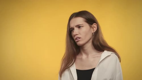 Brunette Woman Expressing Discomfort on Yellow Backdrop