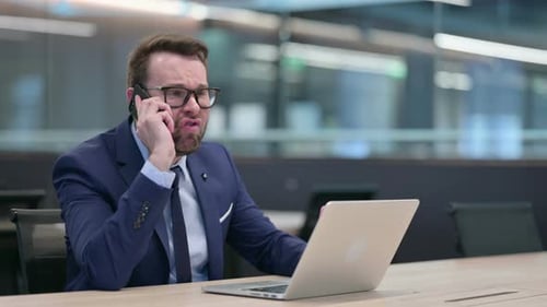 Furious Man Yelling on Mobile Phone in Office